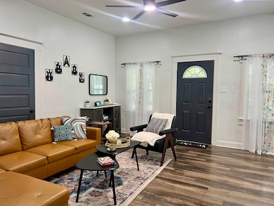 Living room with a ceiling fan, dark wood-style fl