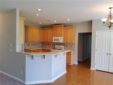 Kitchen featuring light countertops, a peninsula, white appliances, tasteful backsplash, and a breakfast bar area