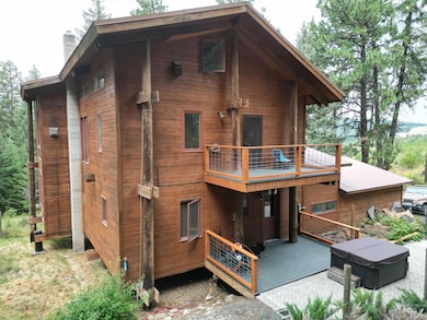 Back of house with a balcony, a chimney, and a wooden deck
