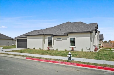 View of front of home featuring a garage, a front yard, a shingled roof, and stucco siding