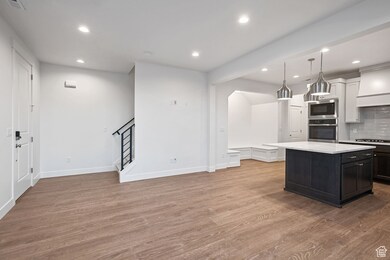 Kitchen with decorative backsplash, recessed lighting, dark wood-style flooring, appliances with stainless steel finishes, and decorative light fixtures