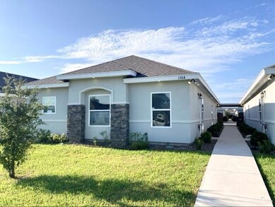 View of front of property with stucco siding, a front lawn, roof with shingles, and stone siding