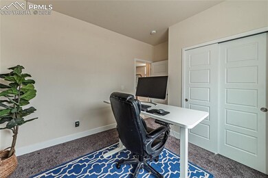 Carpeted home office with baseboards and lofted ceiling