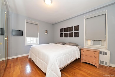 Bedroom featuring hardwood / wood-style flooring, radiator, and cooling unit