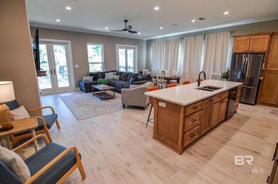 Kitchen featuring brown cabinetry, open floor plan, crown molding, a kitchen breakfast bar, and appliances with stainless steel finishes