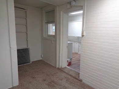 Hall featuring light carpet and brick wall