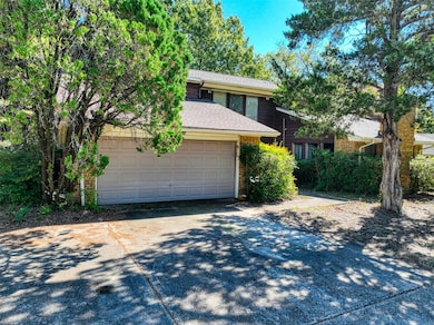 View of front of house with a shingled roof, concrete driveway, brick siding, and a garage