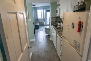 Kitchen with white appliances, white cabinetry, and backsplash