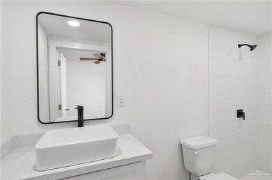 Bathroom with vanity, a tile shower, and toilet