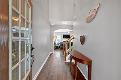 Entryway with arched walkways, wood finished floors, a ceiling fan, and stairway