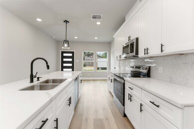 Modern kitchen with sleek white cabinetry, stainless steel appliances, elegant hexagon tile backsplash, and ample natural light. Perfect for culinary enthusiasts.