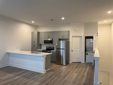 The open-concept living, dining, and kitchen area offers a seamless flow filled with natural light, featuring stylish vinyl plank flooring and a modern, inviting atmosphere perfect for everyday living or entertaining. The kitchen is fully equipped with stainless-steel appliances, sleek cabinetry, and ample counter space—combining functionality and elegance in one bright, contemporary space.