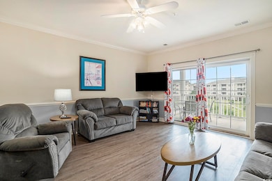 Living room featuring wood finished floors, crown molding, a ceiling fan, and baseboards