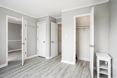Unfurnished bedroom featuring light wood finished floors, multiple closets, and ornamental molding