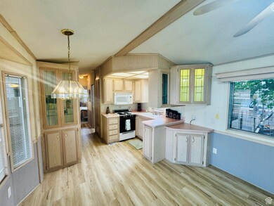 Kitchen featuring light wood-style floors, white appliances, light countertops, a peninsula, and pendant lighting