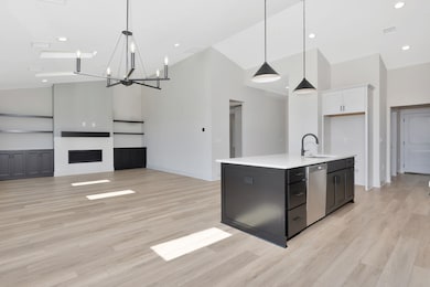 Kitchen with white cabinets, light countertops, high vaulted ceiling, stainless steel dishwasher, and a chandelier