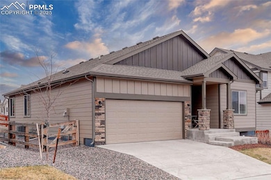 View of front of home featuring concrete driveway, stone siding, board and batten siding, a garage, and a shingled roof