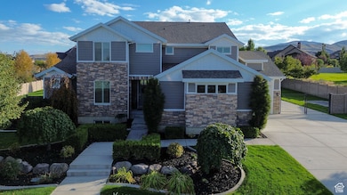 Craftsman-style home featuring stone siding, a shingled roof, driveway, a gate, and board and batten siding