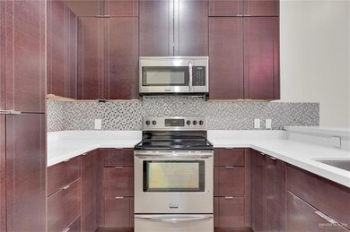 Kitchen featuring appliances with stainless steel finishes, modern cabinets, reddish brown cabinets, and light countertops