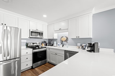 Kitchen with appliances with stainless steel finishes, white cabinetry, light countertops, recessed lighting, and ornamental molding