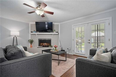 Living area featuring ornamental molding, wood finished floors, a fireplace, a textured ceiling, and a ceiling fan