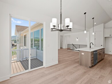 Kitchen featuring light wood-type flooring, a chandelier, stainless steel dishwasher, plenty of natural light, and lofted ceiling