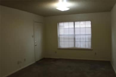 Spare room featuring dark colored carpet and baseb