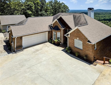 View of front of house with concrete driveway, brick siding, an attached garage, a chimney, and a shingled roof