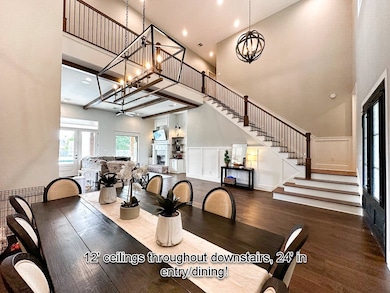 Dining area with wood finished floors, a towering ceiling, stairway, and an inviting chandelier