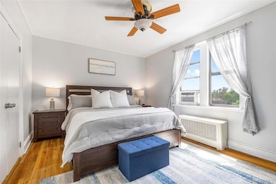 Bedroom featuring radiator heating unit, wood finished floors, a ceiling fan, and cooling unit