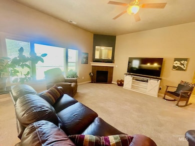Living area featuring carpet, a tiled fireplace, and ceiling fan
