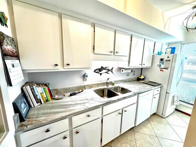 Kitchen with sink, white appliances, light tile pa