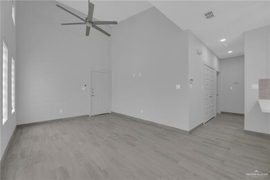 Spare room with light wood-type flooring, ceiling fan, and high vaulted ceiling