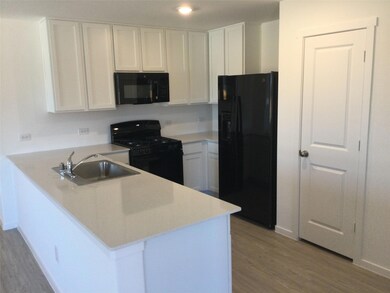 Kitchen featuring a peninsula, black appliances, white cabinets, and a sink.  Walk-in pantry.