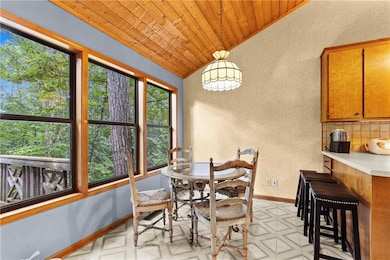 Dining room featuring lofted ceiling, a textured wall, wood ceiling, and light flooring