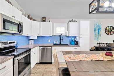 Kitchen with appliances with stainless steel finishes, decorative backsplash, white cabinets, light tile patterned floors, and light stone counters