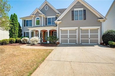 Traditional home featuring covered porch, a front yard, driveway, and a garage