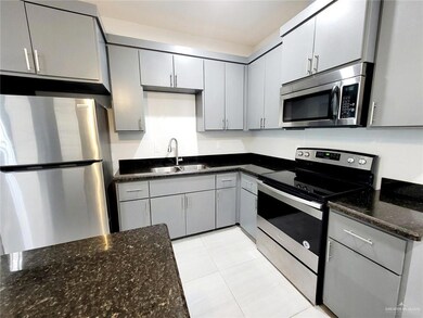 Kitchen featuring dark stone counters, gray cabinetry, appliances with stainless steel finishes, and a sink