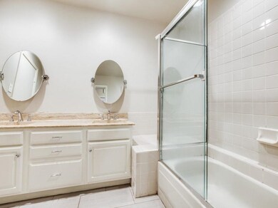 Full bath with double vanity, a sink, and shower / bath combination with glass door