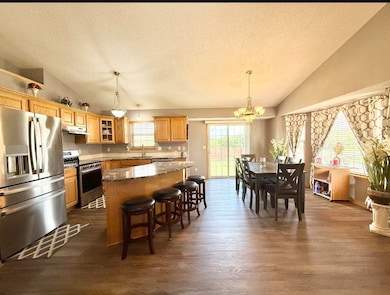 Kitchen featuring stainless steel appliances, under cabinet range hood, vaulted ceiling, a sink, and a textured ceiling