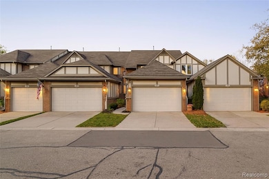 Tudor house with brick siding, concrete driveway, stucco siding, and a shingled roof