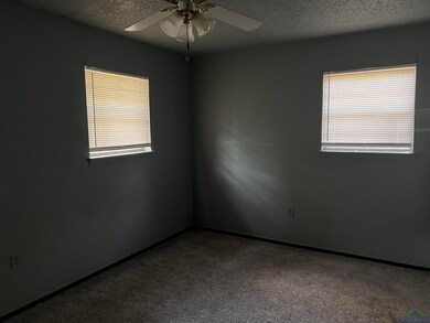 Carpeted empty room with plenty of natural light, a textured ceiling, and a ceiling fan