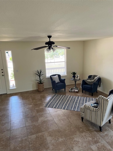 Living area with a ceiling fan, baseboards, a tex