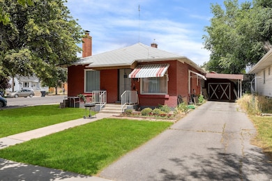 Bungalow featuring a front yard, a chimney, brick siding, and driveway