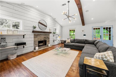 Living room with a chandelier, a tiled fireplace, wooden walls, wood finished floors, and recessed lighting