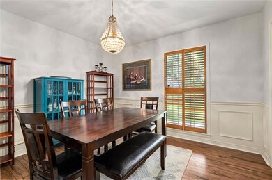 Dining room featuring a chandelier, hardwood / wood-style flooring, wainscoting, and a decorative wall