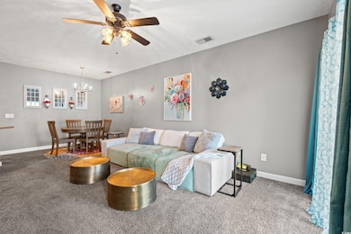 Living room featuring carpet floors, ceiling fan, and a chandelier