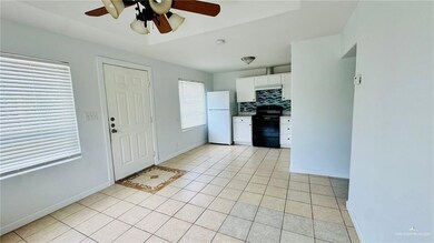 Kitchen featuring freestanding refrigerator, black stove, ceiling fan, white cabinetry, and light tile patterned floors