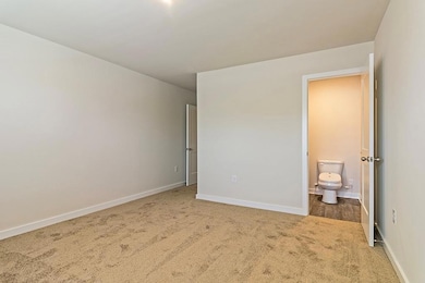 Unfurnished bedroom with dark carpet and ensuite b