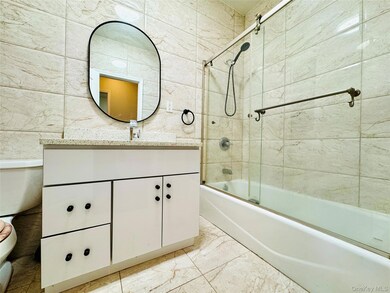 Bathroom featuring vanity, bath / shower combo with glass door, and light marble finish flooring